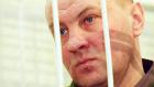 Russian Colonel Yuri Budanov looks out from a cage during his trial in Rostov-on-Don. (Reuters)