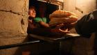Syrian men line up to buy bread at the only bakery still open in the city of Al-Bueda. (File photo: AFP)