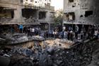 Palestinian men gather around a crater caused by an Israeli air strike on the al-Dallu family's home in Gaza City on November 18, 2012. (Marco Longari / AFP / Getty Images)